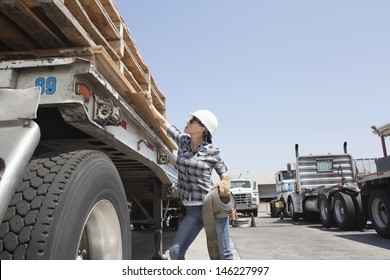 Female industrial worker strapping down wooden planks on logging truck