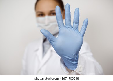 a female infectious disease doctor in a protective mask and medical gloves on a white background, held out her hand in front of her. Theme of Korona Virus. Epidemic and Pandemic infection
