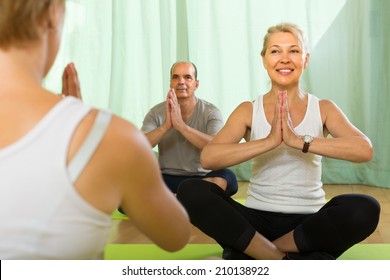 Female Instructor And Mature Couple Practicing Yoga