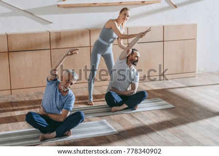 female instructor training with mature men in fitness studio