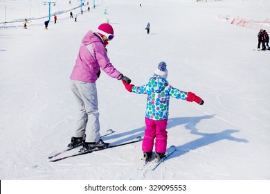 Female Instructors Teach A Child Skiing On Winter Resort