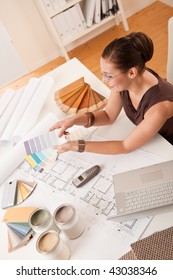 Female Interior Designer With Color Swatches And Laptop At Office