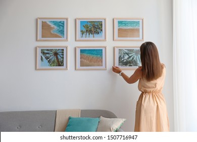 Female Interior Designer Decorating White Wall With Pictures Indoors