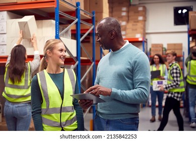 Female Intern With Team Leader Looking At Digital Tablet Inside Busy Warehouse Facility - Powered by Shutterstock