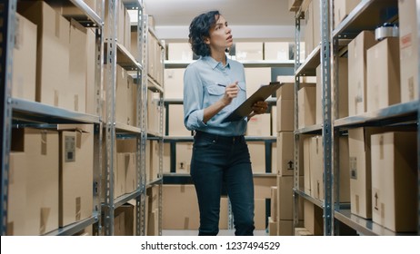 Female Inventory Manager Checks Stock, Writing in the Clipboard. Beautiful Woman Working in a Warehouse Storeroom with Rows of Shelves Full Of Cardboard Boxes, Parcels, Packages Ready for Shipment. - Powered by Shutterstock