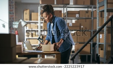 Female Inventory Manager Using Laptop Computer in Storeroom, Preparing a Small Cardboard Box for Postage. Black Multiethnic Small Business Owner Working in Warehouse, Fulfilling Order for Client.