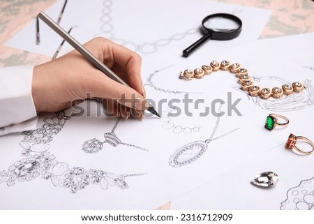 Female jeweler drawing adornment on grunge table, closeup