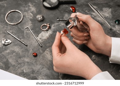 Female jeweler examining ring on dark table, closeup - Shutterstock ID 2316712999