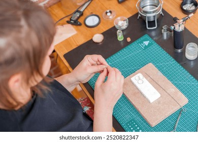 Female jeweler making handmade jewelry at her home studio using a blowtorch and other tools. - Powered by Shutterstock