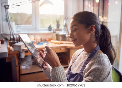 Female Jeweller Comparing Ring With Drawn Design On Digital Tablet In Studio - Powered by Shutterstock