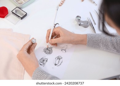 Female jewelry designer drawing sketch for stylish accessory at workplace - Powered by Shutterstock