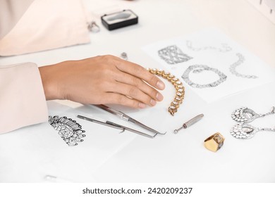 Female jewelry designer working with sketches of stylish accessories in office - Powered by Shutterstock