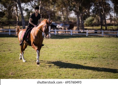 Female Jockey Riding Horse At Equestrian Center