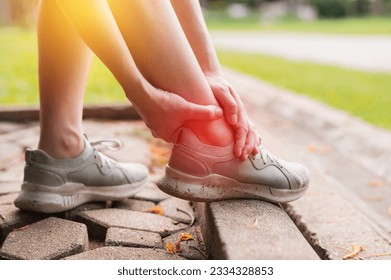 female joggers pain and discomfort after running in the public park. care and treatment for ankle injuries concept.