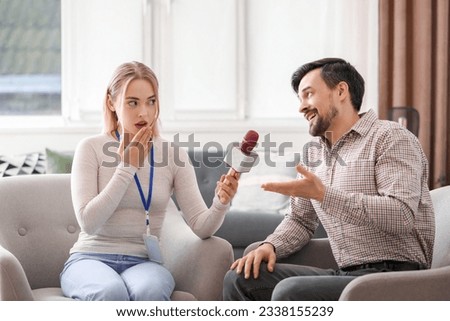 Female journalist with microphone having an interview with man in studio