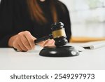 Female judge in black robe holding a gavel poised above sound block symbolizing legal authority and justice