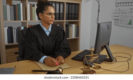 Female judge working at a desk in an office setting, wearing judicial robe with legal books in the background and scales of justice on the table - Powered by Shutterstock