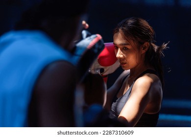 Female kickboxing training with male trainer gives self-defense classes to female fighter at GYM. Asian beautiful young woman exercise with trainer at boxing gloves, uppercut short, boxing, training