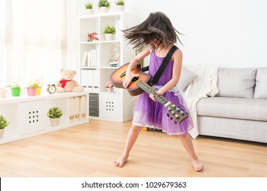 The Female Kid Playing In The Living Room Imagine Herself A Super Rock Star. Shaking Her Head So Hard And Enjoying The Background Music.