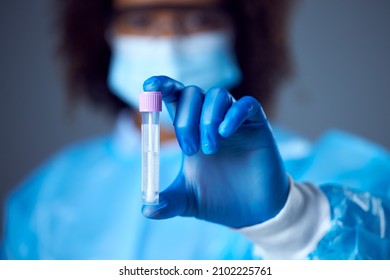 Female Lab Worker In PPE With Safety Glasses And Face Mask Holding Test For Lateral Flow DNA PCR Test - Powered by Shutterstock