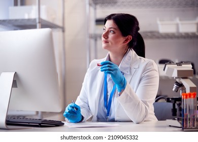 Female Lab Worker Wearing PPE Recording Blood Test Results On Computer