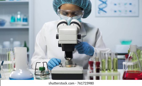 Female laboratory technician looking into microscope, doing biomedical research