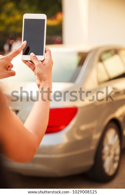 Female Lady using app on smart phone\
device, technology concept. Lady hand using remote control to send\
signal to unlock car doors and trunk in the parking\
lots.