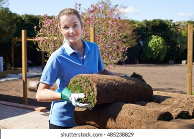 Female Landscape Gardener Laying Turf For New Lawn