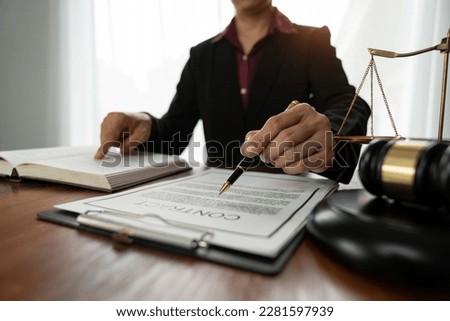Female lawyer or legal counsel sitting at desk reading and reviewing data in file folder, legal book in accordance with the principles of jurisprudence to study and find information.