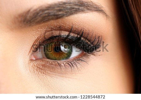 Female left emerald green coloured eye extreme closeup. Low light technique oculist and perfect vision contact lens shadow makeup cosmetics mascara concept