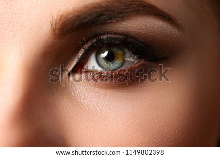 Female left emerald green coloured eye extreme closeup. Low light technique oculist and perfect vision contact lens correction beauty shadow makeup cosmetics mascara concept