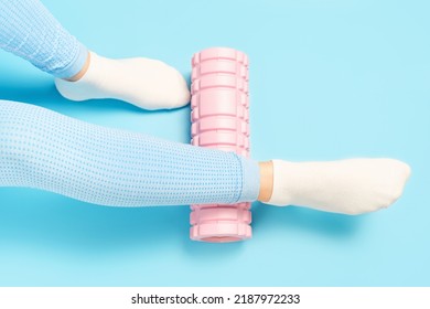 Female leg rolls a massage foam roller close-up on a blue background, top view. - Powered by Shutterstock