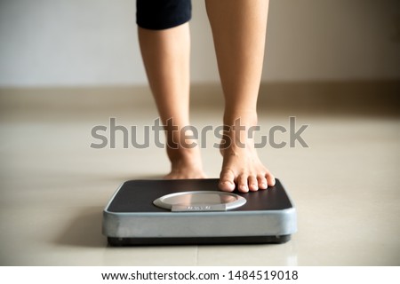 Female leg stepping on weigh scales. Healthy lifestyle, food and sport concept.