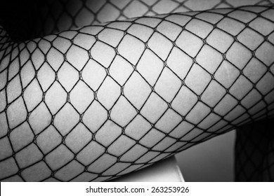 Female legs in black fishnet stockings close up