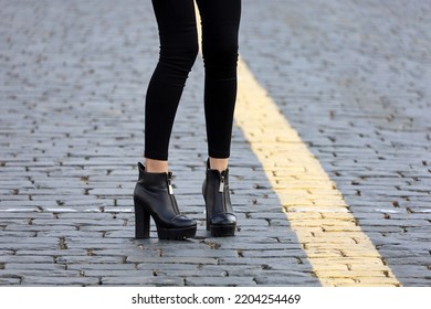 Female Legs In Black Jeans And Boots On High Heels. Slim Girl Standing On A Street, Fashion In Autumn City