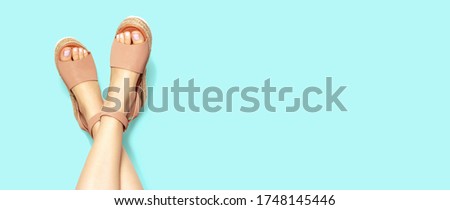 Female legs with blue pedicure in summer brown sandals, on a white background, copy of the space