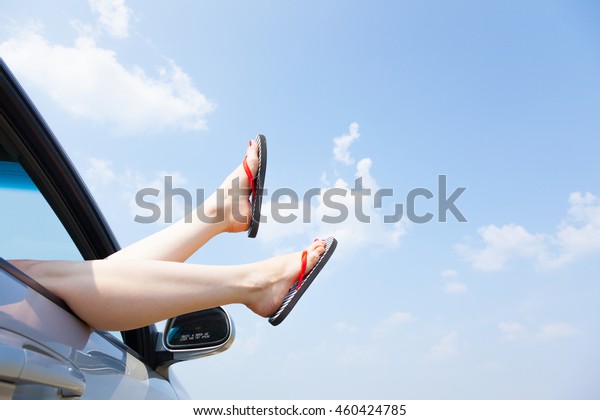 female legs dangling from the open car window in\
the shales
