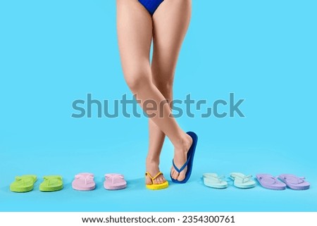 Female legs with different colorful stylish flip flops on blue background