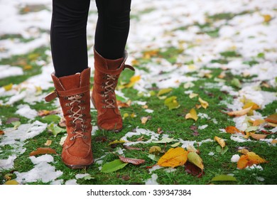 Female legs and fallen autumn leaves on grass background