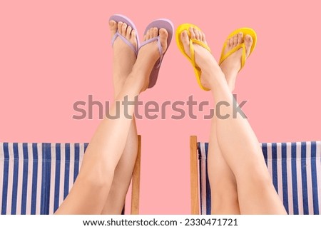 Female legs in flip-flops on pink background