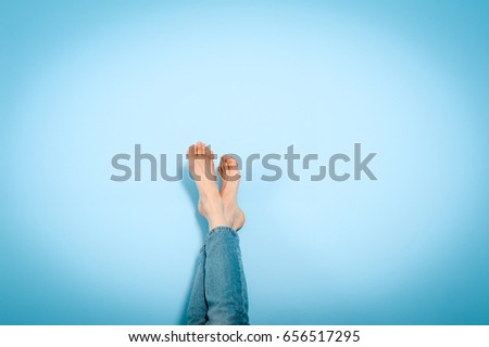Female legs foot on foot on blue wall, resting, holiday