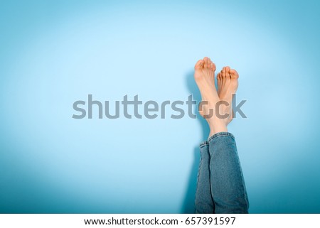 Female legs foot on foot on blue background, resting, holiday