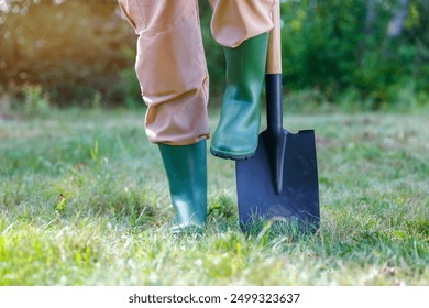 Female legs in green rubber boots and digging with  a spade. Autumn work and cleaning in the garden on a sunny warm autumn day. - Powered by Shutterstock