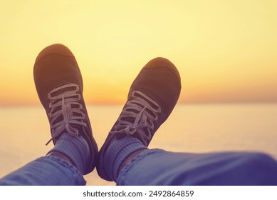 Female legs in green sneakers on the beach against the background of the sky and sea at sunset. An image of fun and relaxation - Powered by Shutterstock