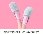 Female legs in grey soft slippers on pink background