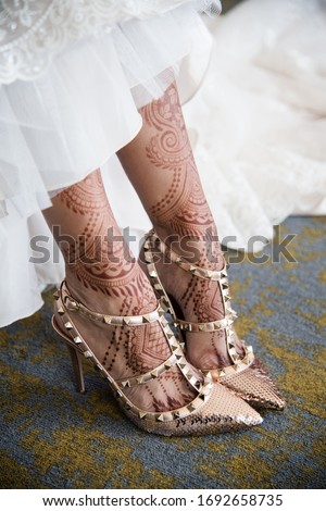 Female legs with henna tattoo. Indian bride's showing mehndi design.  mehndi feet in beautiful female wedding bride shoes with mehndi tattoos. Indian tradition. 