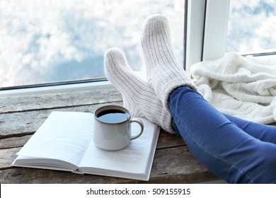 Female legs and hot drink on windowsill