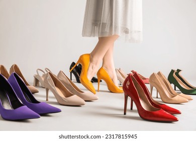 Female legs and many stylish high heels on grey background