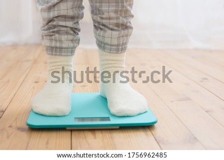 female legs on electronic scales on  wooden floor