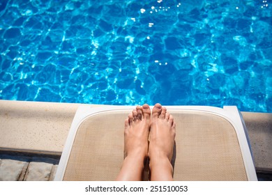 Female Legs On A Sun Lounger On The Background Of The Pool.